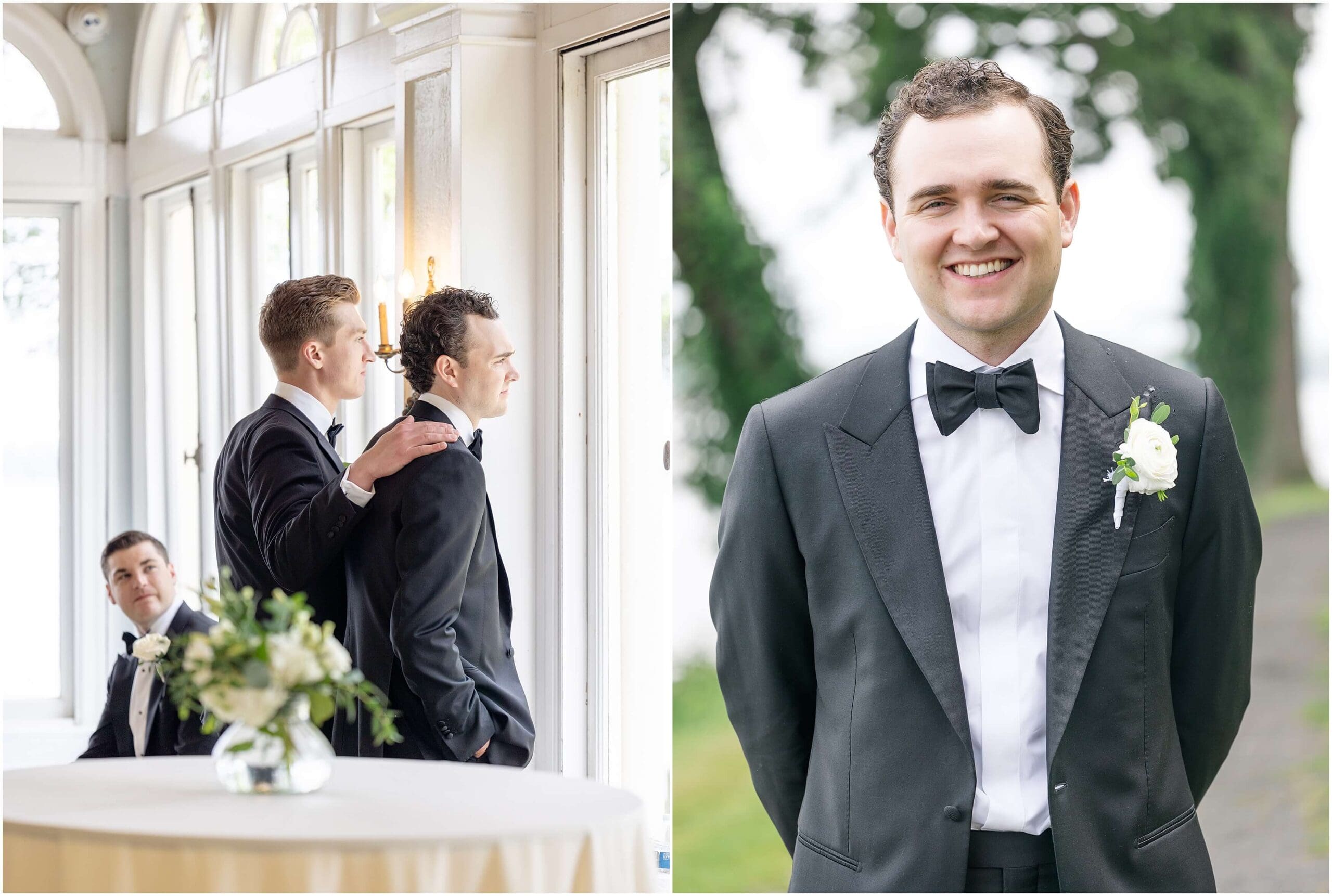 A happy groom smiles in his black tux with hands behind his back next to him with groomsmen looking out a window